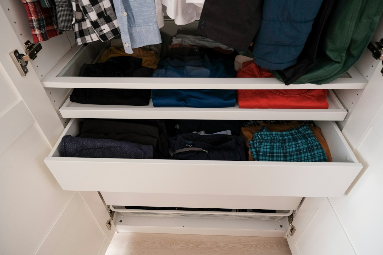 Open wardrobe with pull-out drawers and organised clothing storage